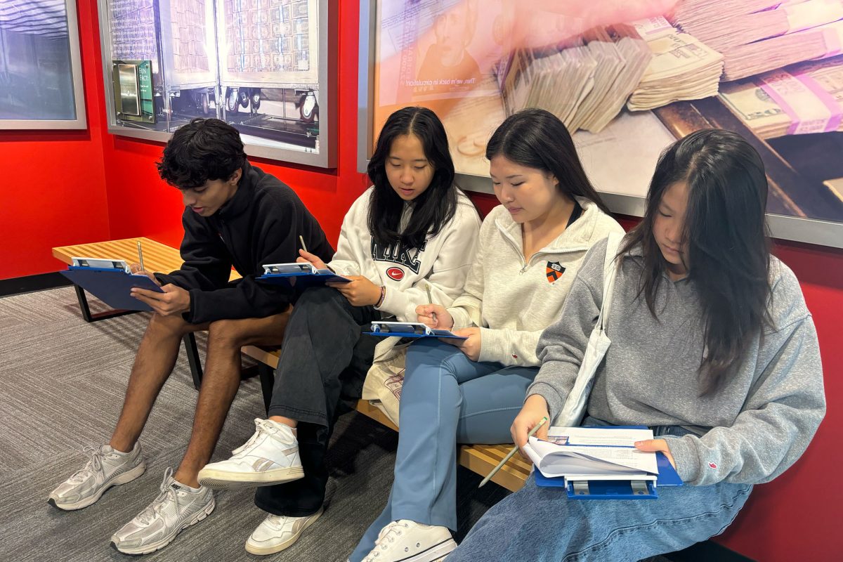 Senior Tarak Oak, Sophia Hung, Christine Han, and Michelle Quan fill out their worksheets for an AP Macroeconomics class at the FRB. 