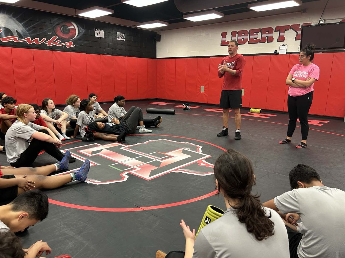 Head coaches Justin Koons and Viviana Espinoza address the Redhawks wrestling team during a recent practice. The team took on both Rock Hill and Lewisville at the start of Thanksgiving break. 