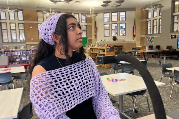 Wearing items she's crotched, junior Anagha Konuru prepares for Thursday's advisory event in the library where she will lead students and staff members in a crochet lesson. 