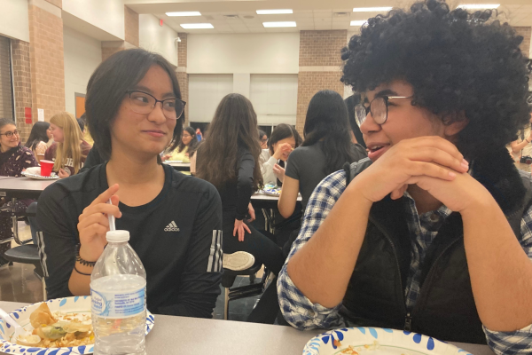 The multicultural potluck gave students across various fine arts, including band, orchestra, and Red Rhythm, to simultaneously share their culture and experiences. Pictured above, sophomores Palistha Shakya and Valerie Nanton connect with each other and eat food.