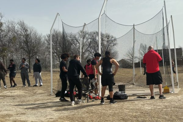 Field athletes in the throwing events gather around coach Joshua Rebmann as the Redhawks prepare to take on Braswell High School Friday. 