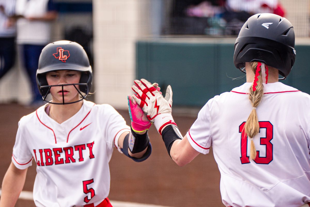 Senior utility player pitcher/pitcher Addison Hanson (#13) high-fives freshman pitcher Beckley Baumgart (#5) during a game.

